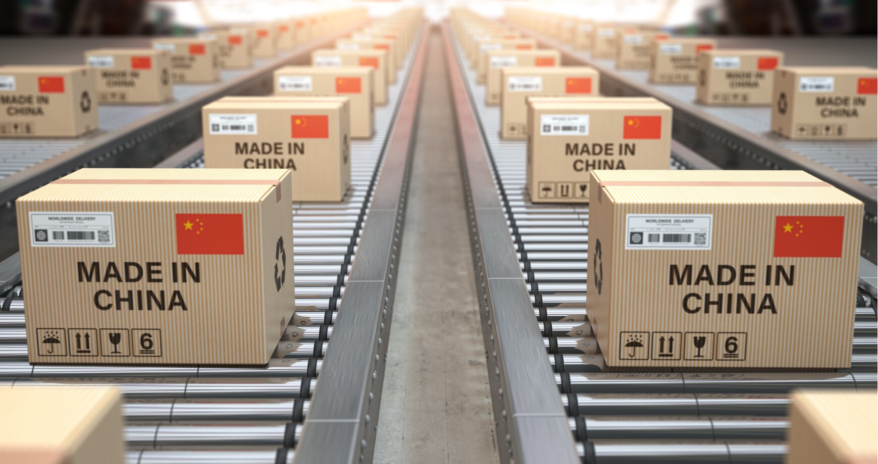 Zdjęcie przedstawia cztery rolkowe, przesuwne linie transportowe, znajdujące się prawdopodobnie w magazynie. Na rolkach znajduje się duża ilość, identycznych papierowych kartonów, ustawionych w takiej samej odległości od siebie. Na kartonach w lewym górnym rogu znajduje się naklejka z kodem kreskowym. Po prawej na górze znajduje się flaga Chin. Poniżej napis MADE IN CHINA. W lewym dolnym rogu znajdują się cztery znaki informacyjne, określające sposób transportu przesyłki.