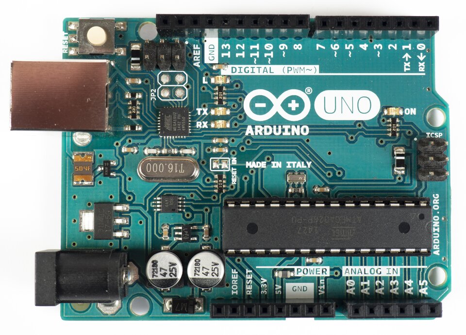 Zdjęcie przedstawia prostokątną, zieloną płytkę Arduino Uno, na której zamocowano różne małe elementy. Na płytce są dwa kółka - w środku jednego z nich jest minus, w środku drugiego plus. Pod nimi jest napis: ARDUINO, obok nich napis: UNO. Widoczne są także napisy: DIGITAL, POWER, ANALOG IN, T16.000. Na płytce widać kilka zamocowanych prostokątnych oraz innych drobnych elementów, a także z linii i dziurek.  
