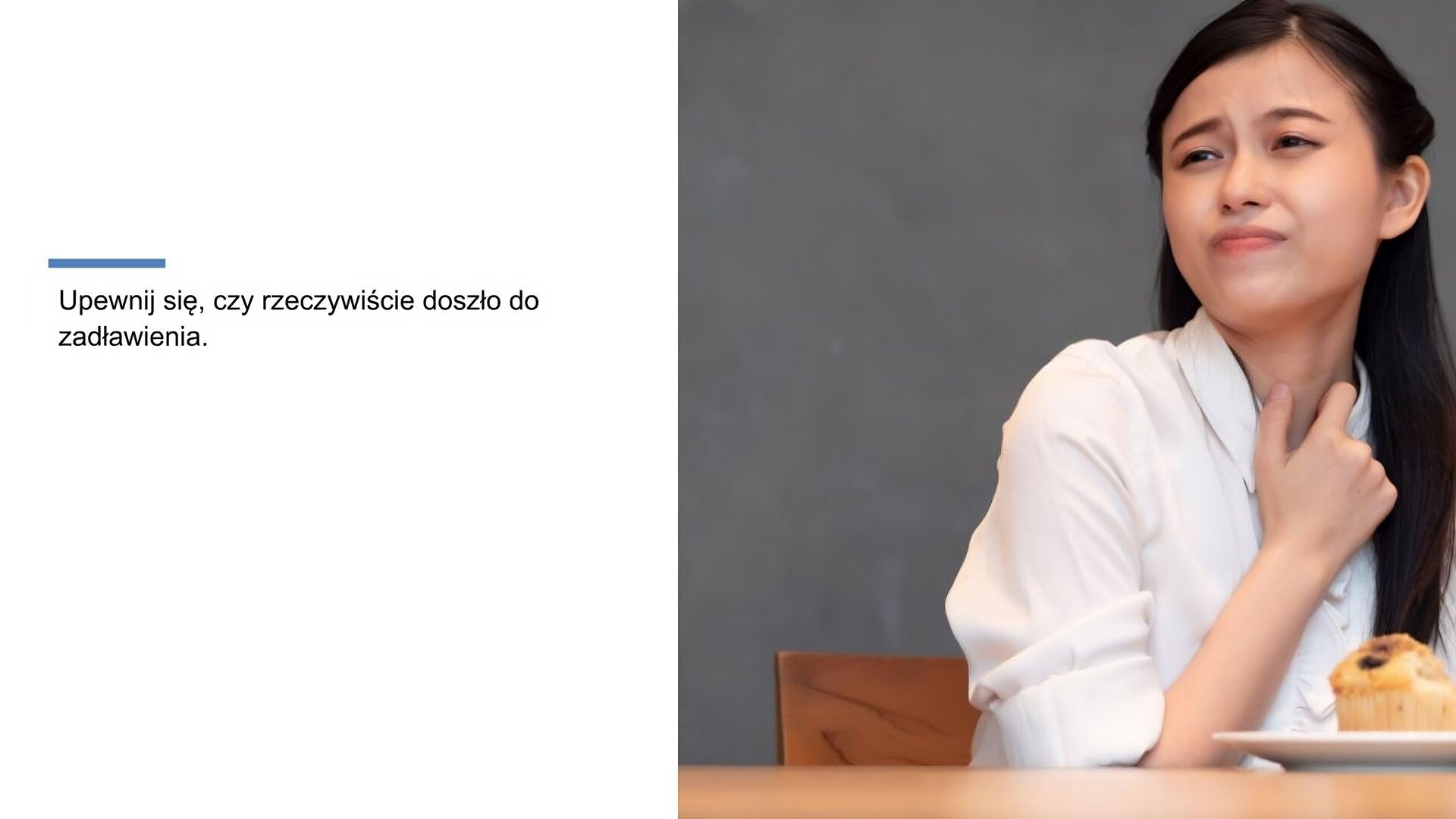Biały slajd. Z lewej strony napis: „Upewnij się, czy rzeczywiście doszło do zadławienia”. Obok, z prawej strony slajdu, młoda kobieta w ciemnych włosach i białej koszuli. Krzywi się i przykłada prawą dłoń do gardła. Przed nią, na stole, stoi biały talerz, a na nim nadgryziona babeczka.