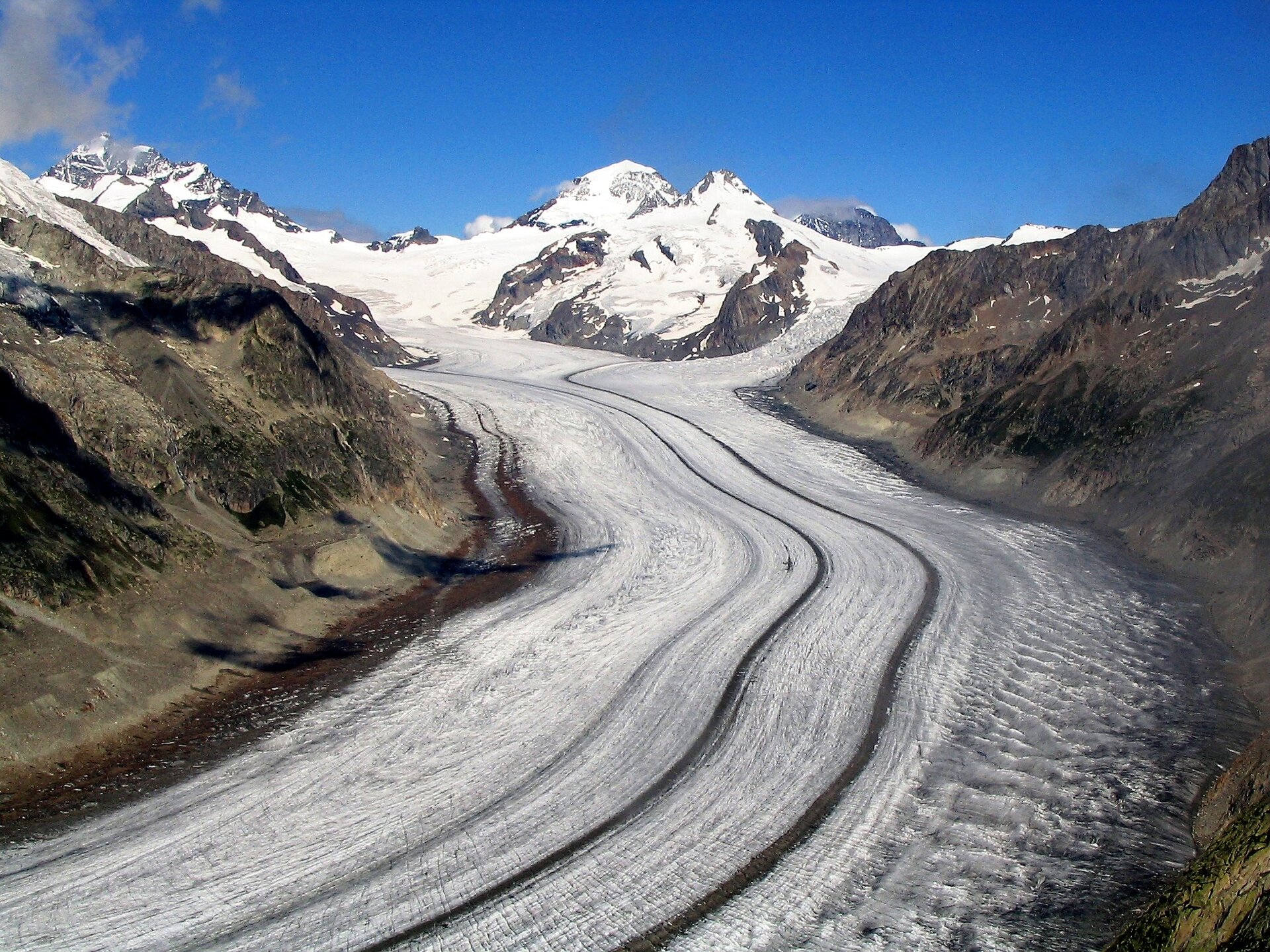 Zdjęcie przedstawia lodowiec Aletsch w Alpach - najdłuższy górski lodowiec alpejski. Jęzor lodowca przypomina szeroką, drogę z lodu schodzącą od szczytów górskich w dół.  