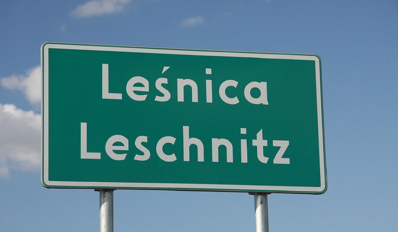 Zdjęcie przedstawia tablicę drogową z dwoma napisami: Leśnica oraz pod spodem Leschnitz.