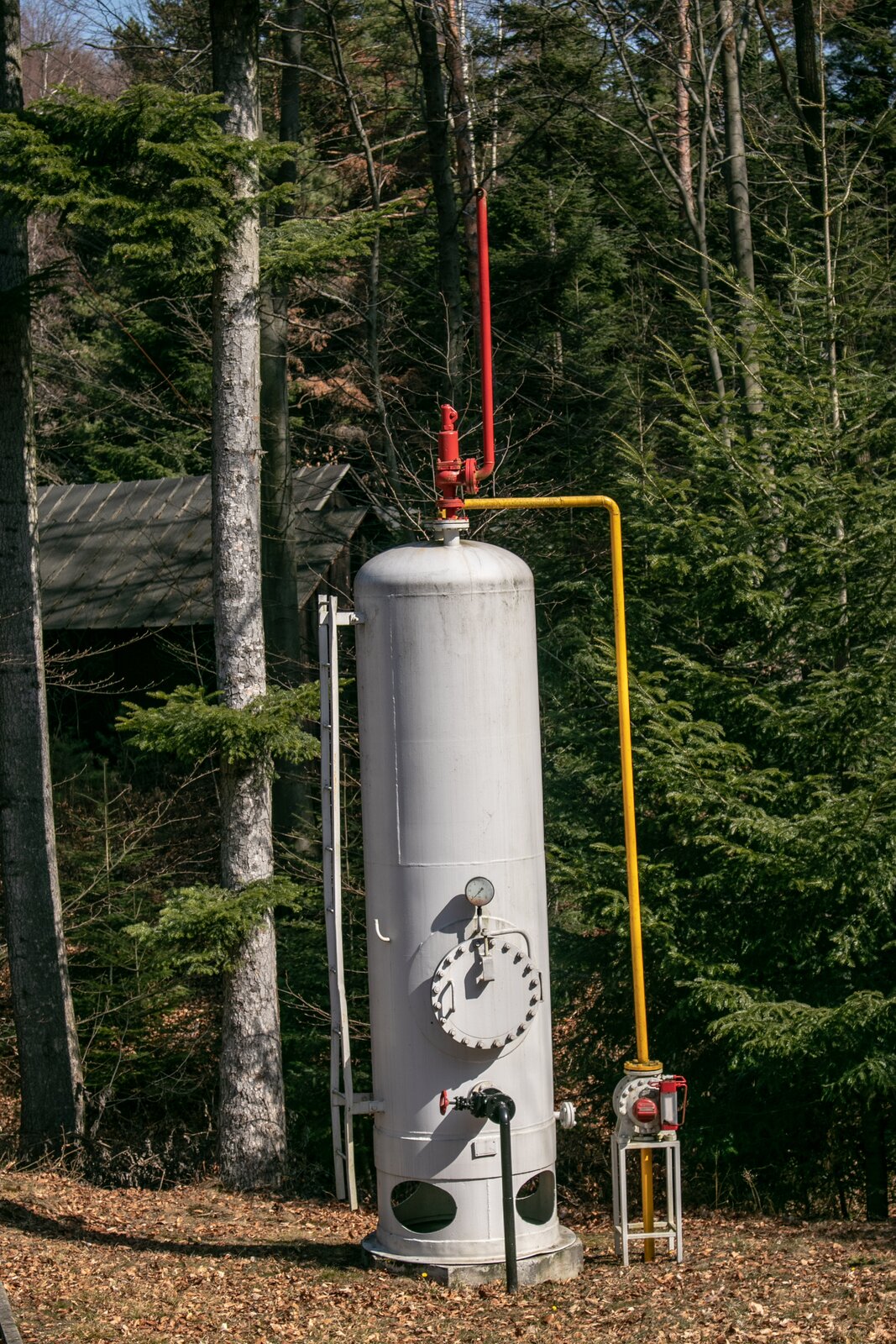 Na zdjęciu widać stalowy separator dwufazowy pionowy typu R <math aria‑label="dziesięć łamane na tysiąc">10/1000, który wykorzystywany jest do rozdziału fazy gazowej od ciekłej. U góry separatora znajduje się czerwony zawór bezpieczeństwa w kształcie odwróconej fajki skierowanej szyjką do góry. Z prawej strony separatora biegnie równolegle do niego cienka stalowa rura. Rura przyłącza się do separatora w miejscu zlokalizowanym pod zaworem bezpieczeństwa. Rura ta wykorzystywana jest do wyprowadzenia gazu. U podstawy rury znajduje się czerwony gazomierz z ekranem ciekłokrystalicznym, który wykorzystywany jest do pomiaru przepływającego gazu. Na dole separatora znajduje się przyłączona do niego czarna cienka rura która zakończona jest od strony separatora czerwonym kurkiem. Jest to zawór spustowy. Powyżej przyłącza rury na separatorze zamontowany jest okrągły manometr, który za pomocą wskazówki pokazuje wartość ciśnienia w zbiorniku. Za separatorem znajdują się drzewa iglaste.