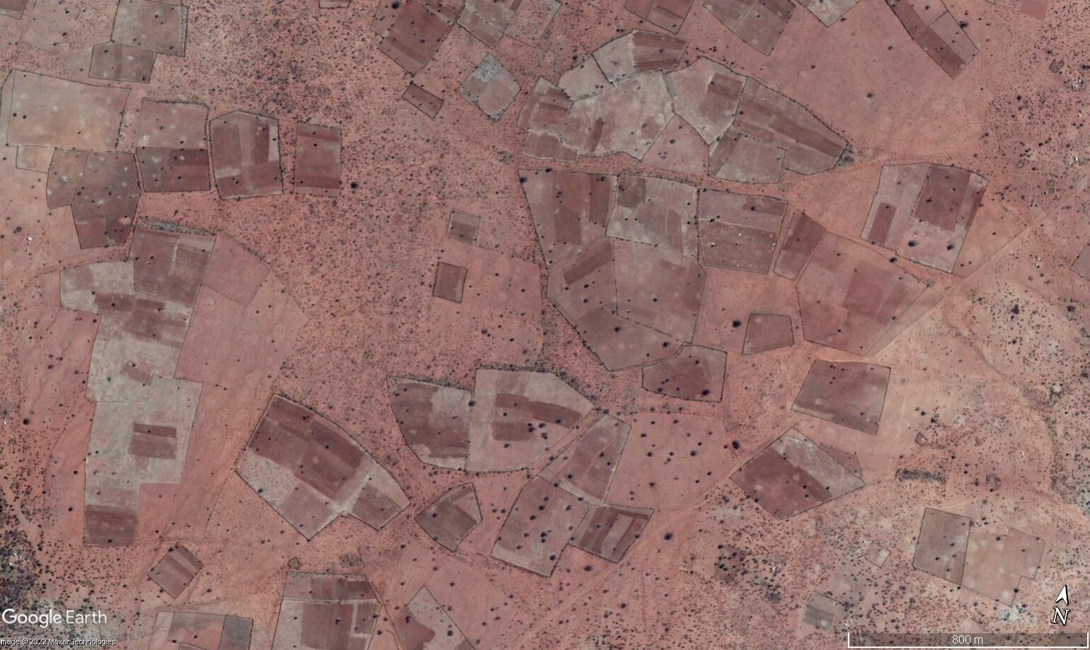 Ilustracja przedstawia ogrodzone pola uprawne pod miastem Chafutchi na południu Zimbabwe. Na zdjęciu satelitarnym widać nieregularnie położone, w różnych odległościach od siebie pola uprawne. Gleba jest wysuszona, brak zieleni.