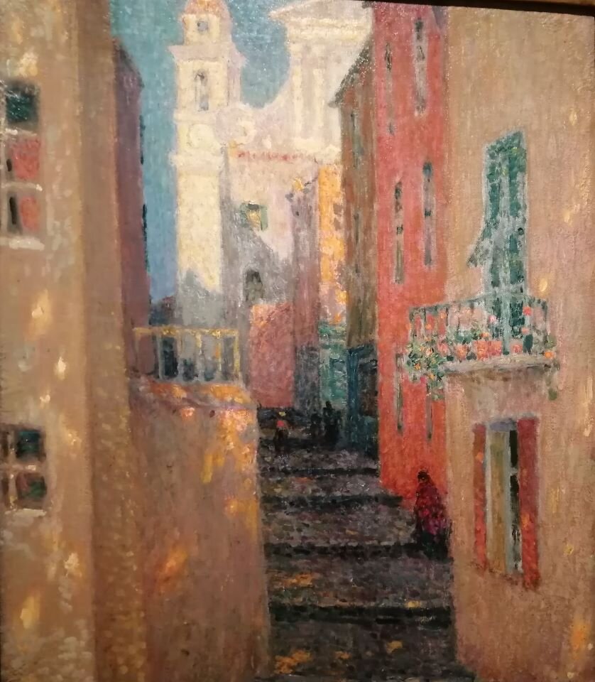 Ilustracja przedstawia fotografię obrazu, na którym znajduje się pejzaż miejski. W kadrze znajduje się fragment wąskiego przejścia między zabudowaniami. Na końcu schodków, w tle widoczny jest monumentalny budynek w jasnych, zimnych odcieniach koloru beżowego. 