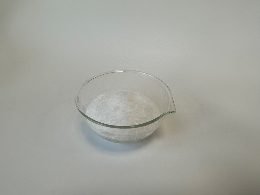 Zdjęcie przedstawia szklaną miskę z białą zawiesiną - mikrowoskiem.
