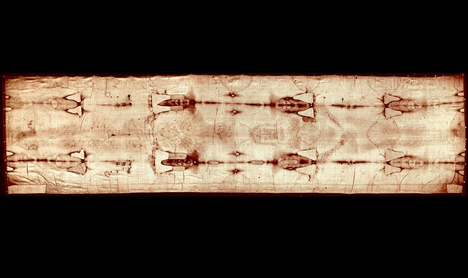 Zdjęcie przedstawia lniane płótno, na którym odbite są czerwone podłużne wzory. 