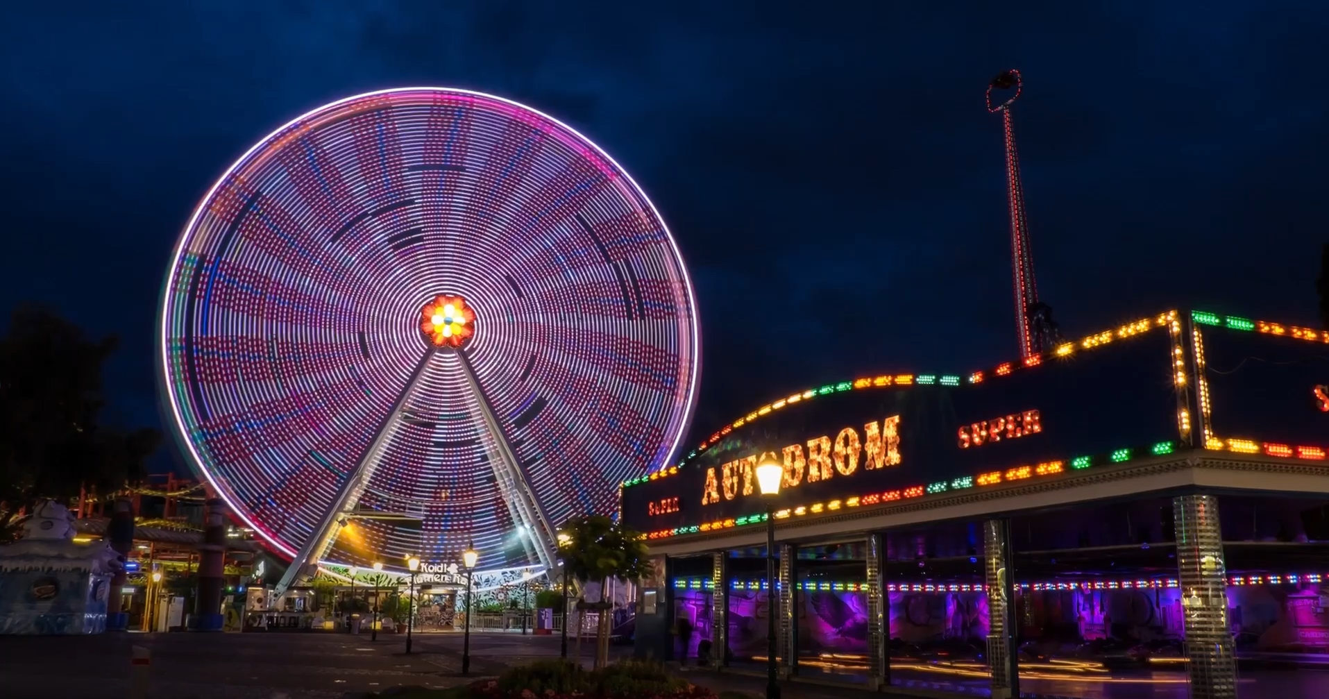 Ilustracja przedstawia Prater - park w Wiedniu. Na pierwszym planie widać wesołe miasteczko z diabelskim kołem.