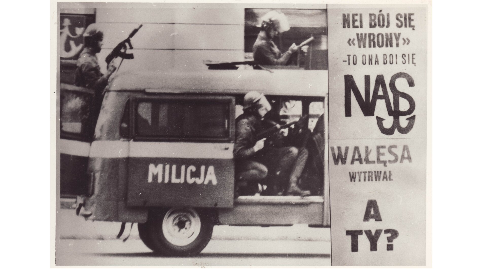 Czarno-biała fotografia przedstawiająca zdjęcie rozpowszechnione nielegalnie w stanie wojennym. Po prawej stronie hasła protestacyjne: Nie bój się Wrony, to ona boi się nas; Wałęsa wytrwał, a ty? Po lewej funkcjonariusze ZOMO w mundurach bojowych i z bronią w milicyjnej nysce.