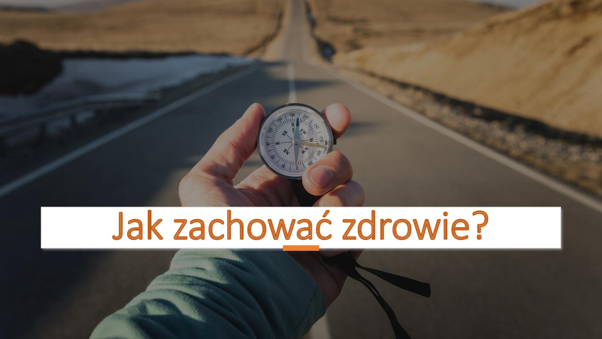 Zdjęcie przedstawia drogę. Z obu stron płaska, piaskowa powierzchnia. Na środku drogi dłoń, która trzyma kompas. W dolnej części slajdu, na białym tle, pomarańczowy napis: „Jak zachować zdrowie?”.