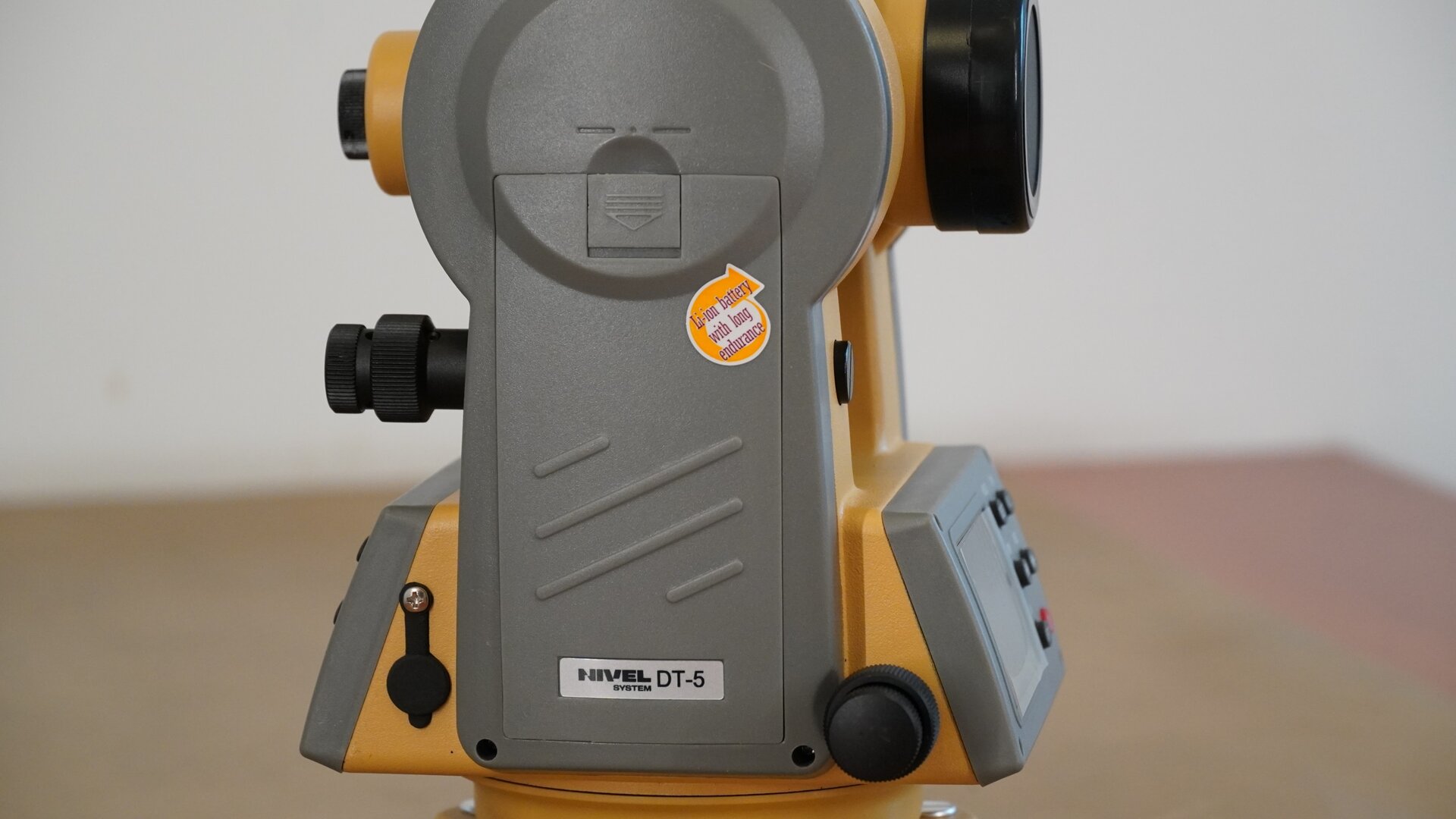 Zdjęcie przedstawia widok teodolitu z bocznej perspektywy. Widać na nim miejsce, w którym umieszcza się baterie.