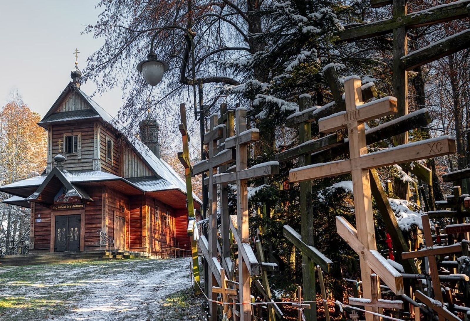 Zdjęcie przedstawia drewnianą cerkiew na św. Górze Grabarce na Podlasiu. Wokół cerkwi, wśród drzew, ustawionych zostało mnóstwo krzyży, które przez lata wnosili tu pielgrzymi.  
