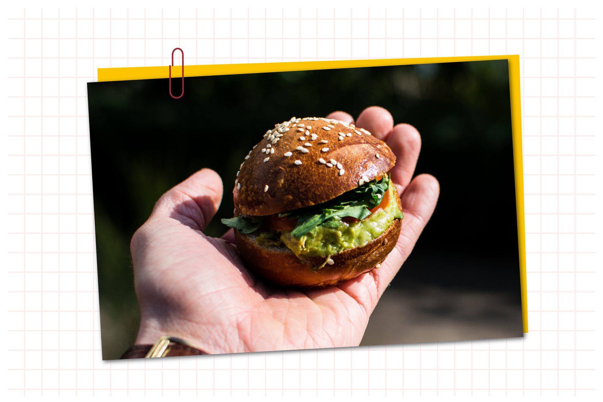 Zdjęcie przedstawia osobę trzymającą w ręku małego hamburgera z guacamole.