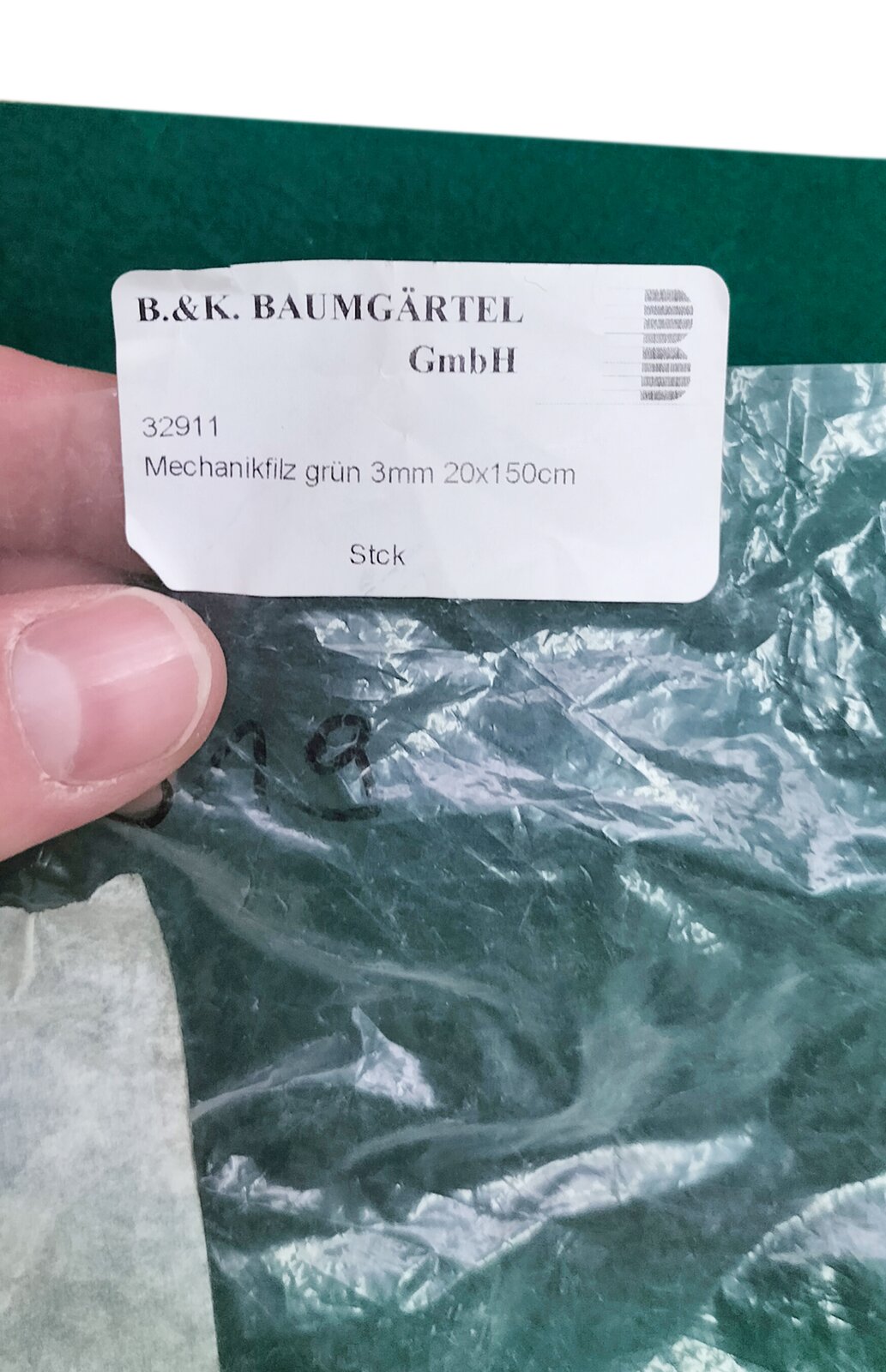 Zdjęcie przedstawia filc bity stosowany do mechanizmach fortepianowych na listwę oporową młotków. Widoczny jest płat filcu bitego w kolorze zielonym, w przeźroczystym foliowym opakowaniu z białą etykietą z czarnymi napisami.