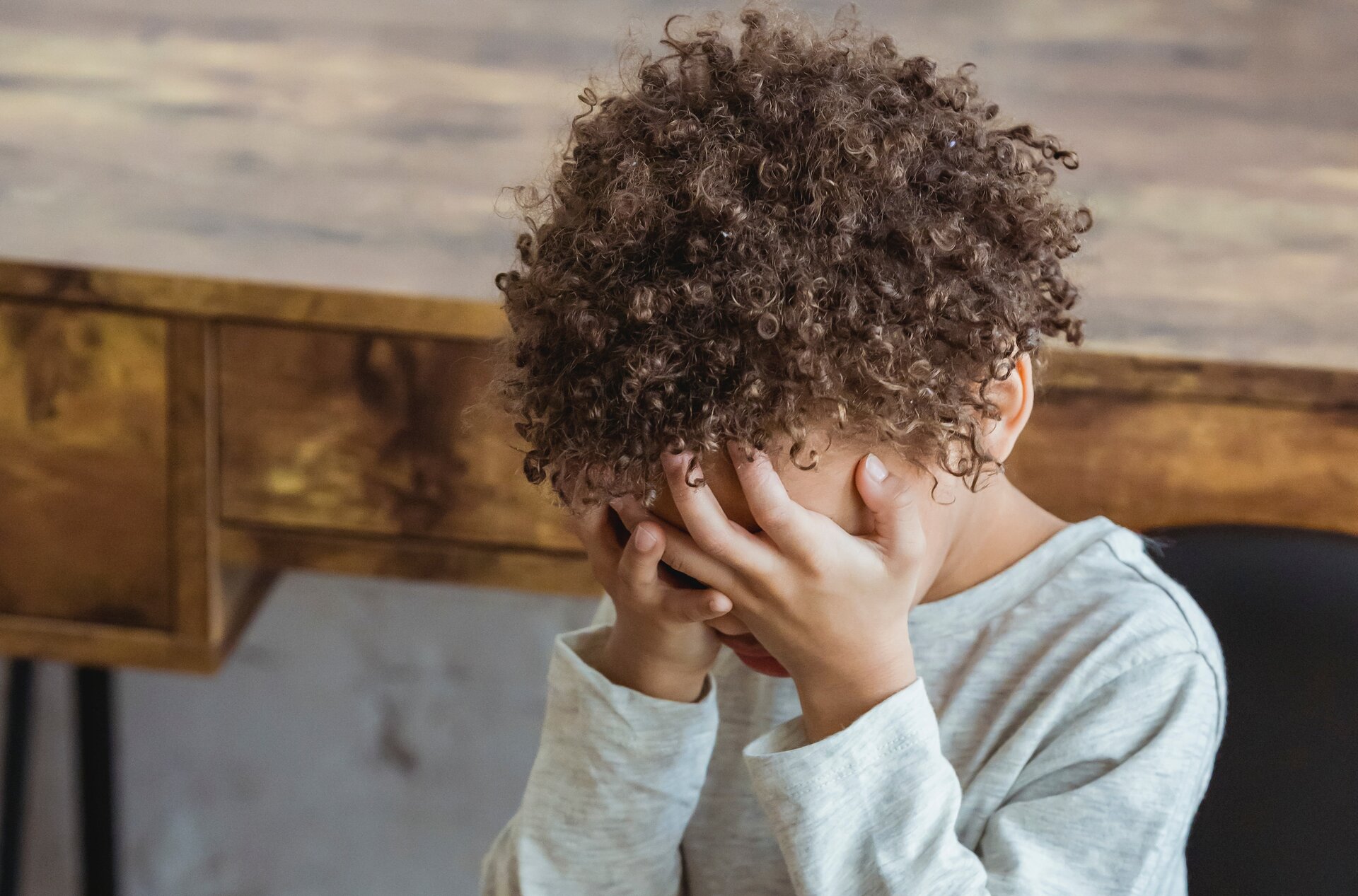 Ilustracja przedstawia chłopca kryjącego twarz w dłoniach.