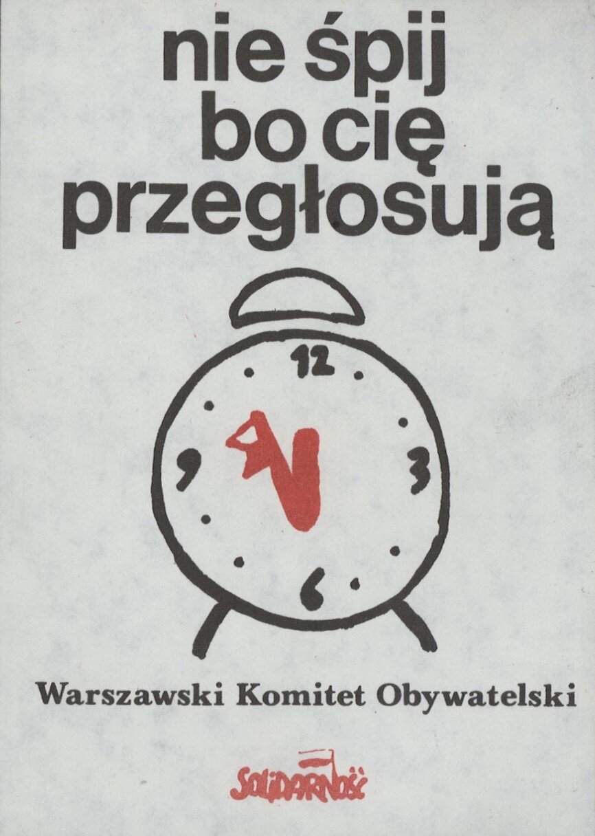 Ilustracja przedstawia plakat. U góry znajduje się hasło: nie śpij bo cię przegłosują. Poniżej narysowano budzik. Wskazówka minutowa zakończona jest biało‑czerwoną flagą. Zegar wskazuje za pięć dwunasta. Pod zegarem podpis: Warszawski Komitet Obywatelski. U dołu logo, czerwone, złączone litery tworzące napis Solidarność. Nad literą N powiewa biało‑czerwona flaga.