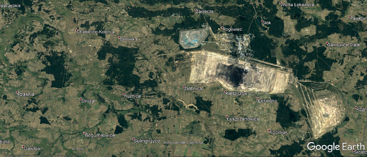 Na zdjęciu satelitarnym jest Zagłębie Górniczo‑Energetyczne Bełchatów–Szczerców–Złoczew w 1996 roku. Na zdjęciu jest jasnożółty prostokąt, po jego prawej stronie jest wzniesienie. Wzniesienie łączy się z prostokątem. Prostokąt ma ciemny środek.  Na zachodzie wyrobisko sięga Zarzecza, Rogowca, Żłobnicy. 