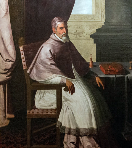 Obraz przedstawia papieża Urbana drugiego. Siedzi on przy stole. Jest ubrany w białe papieskie szaty. Ma krótką siwą brodę. Na stole leżą dwie książki o czerwonych okładkach oraz dzwoneczek. 