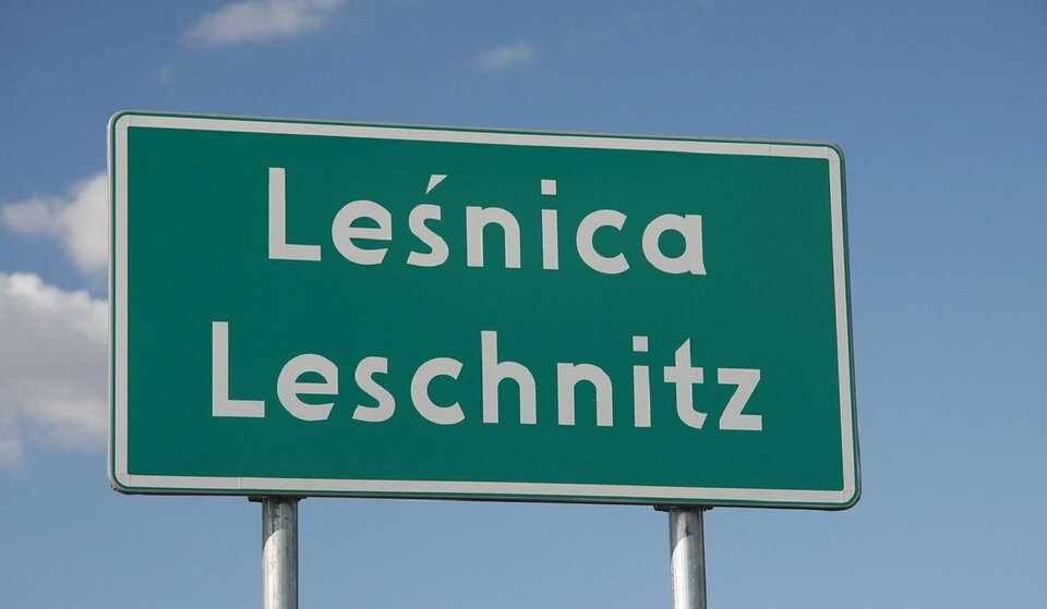 Zdjęcie przedstawia tablicę drogową z dwoma napisami: Leśnica oraz pod spodem Leschnitz.