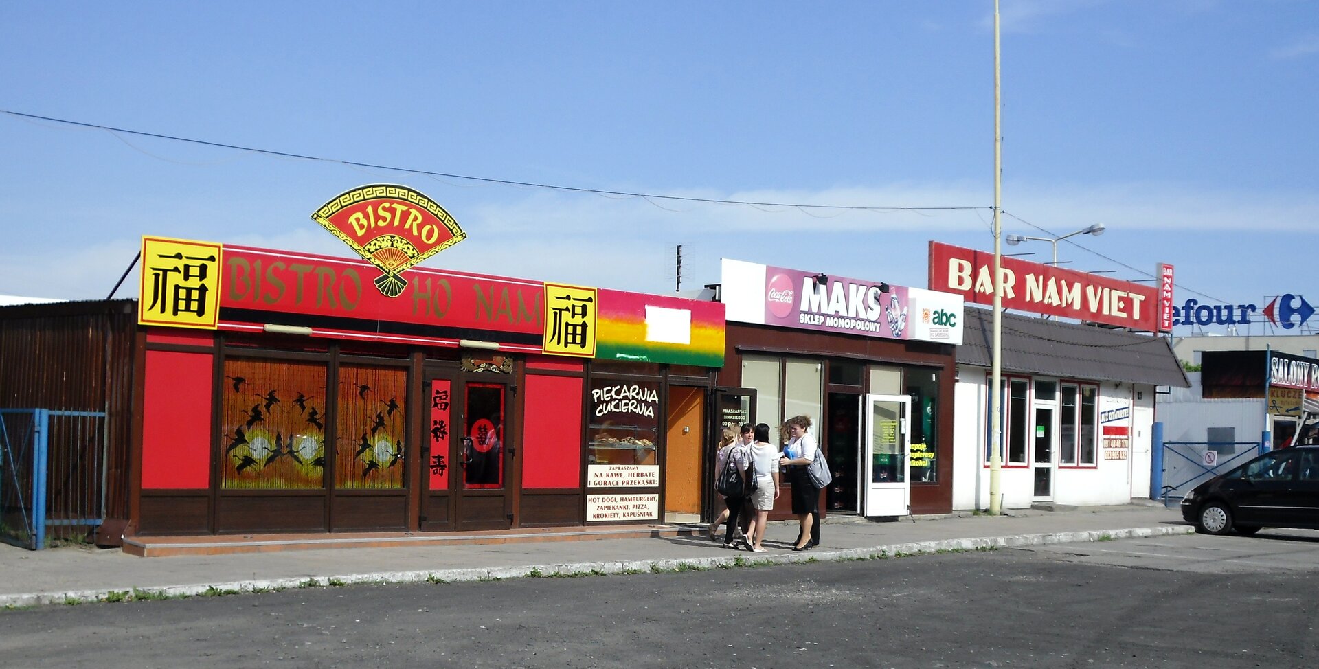 Na zdjęciu zabudowania usługowe, napisy i szyldy w języku wietnamskim.