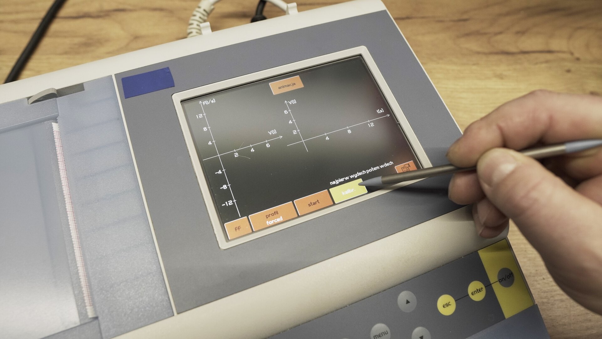 Na zdjęciu pokazano przybliżenie ekranu spirometru. Technik wybiera na klawiaturze ekranowej przycisk kalibracja.