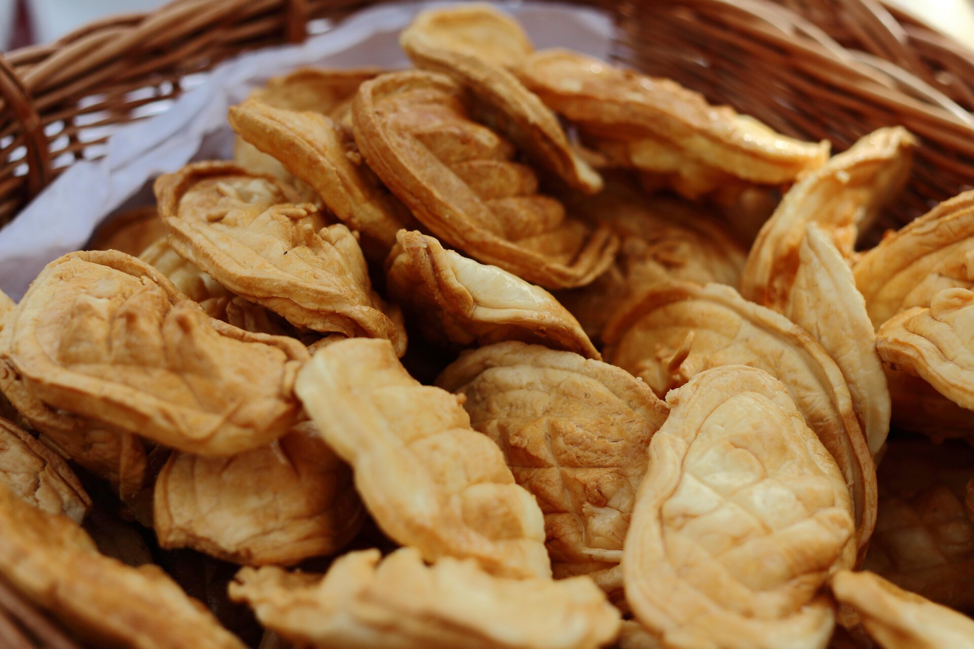 Kliknij aby powiększyć Zdjęcie przedstawia oscypki, które są w kształcie spłaszczonego jaja koloru pomarańczowego. Umieszczone zostały w koszyku wyłożonym serwetką.