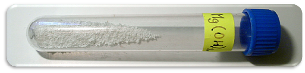 Na zdjęciu zamknięta korkiem probówka. Wewnątrz znajduje się sproszkowana, biała substancja. Na probówce napis: Mg(OH)2. To wodorotlenek magnezu.