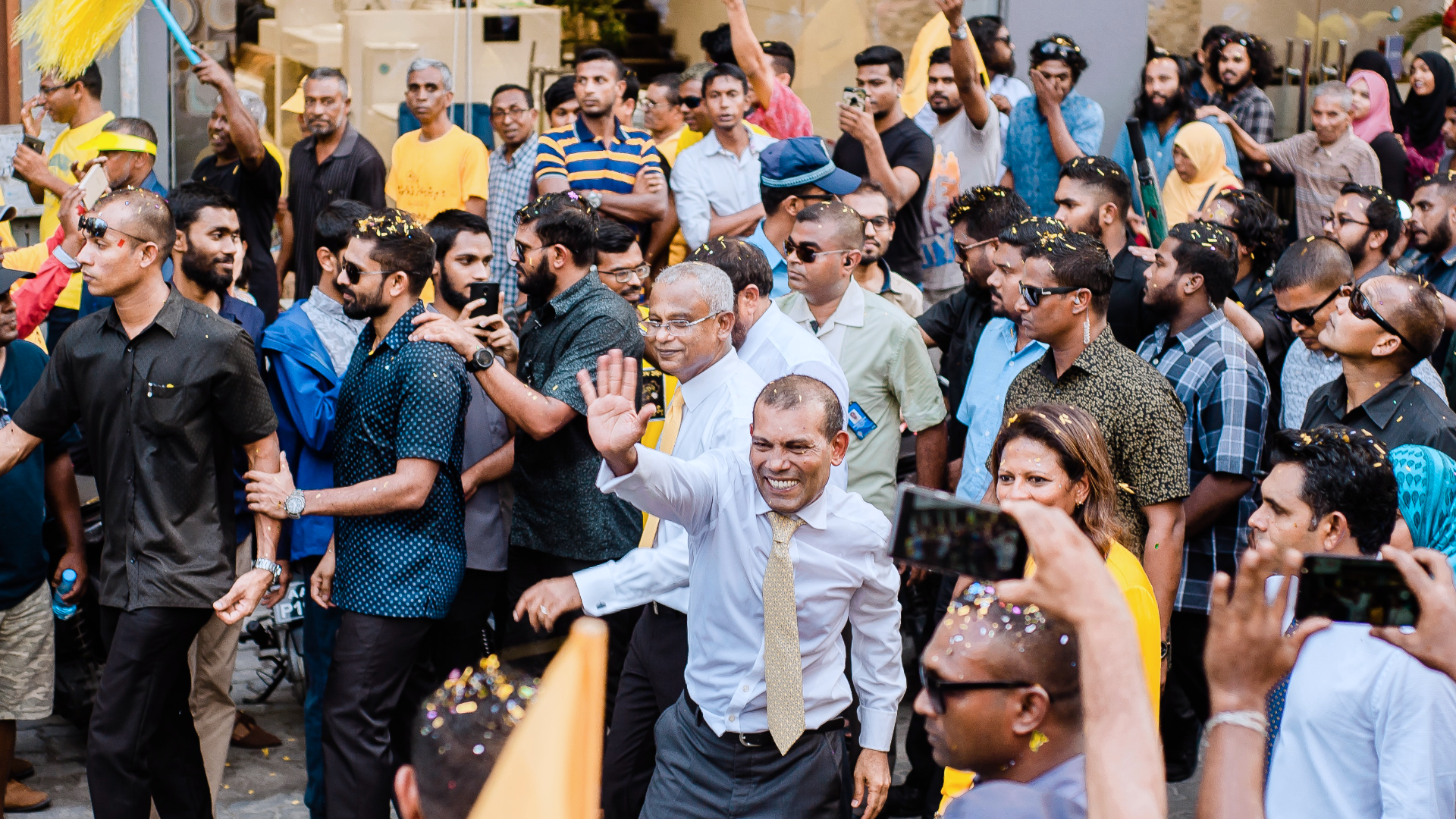 Zdjęcie przedstawia dużą grupę ludzi podczas happeningu. Niektórzy nagrywają telefonami, inni unoszą swoje dłonie.