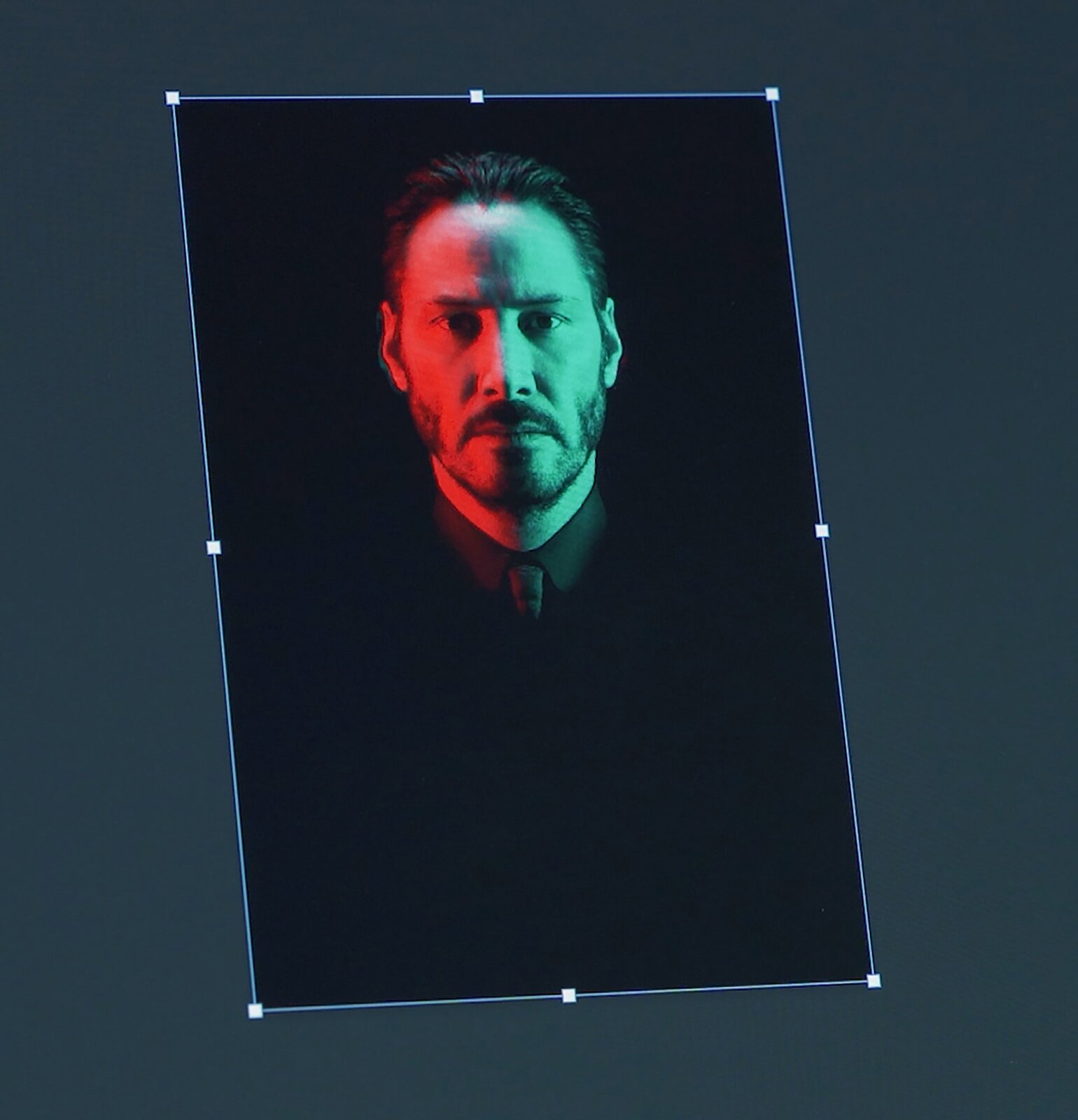 Zdjęcie przedstawia przykładowe skalowanie proporcjonalne. Widoczny jest ciemnoszary kwadrat symbolizujący ekran komputera, ze zdjęciem popiersia mężczyzny, przedstawionym frontalnie, z oświetloną na czerwono i zielono twarzą, na czarnym tle. Wokół czarnego tła widoczna jest ramka z drobnych niebieskich punktów z jaśniejszymi punktami na narożnikach oraz na środku każdej krawędzi ramki.