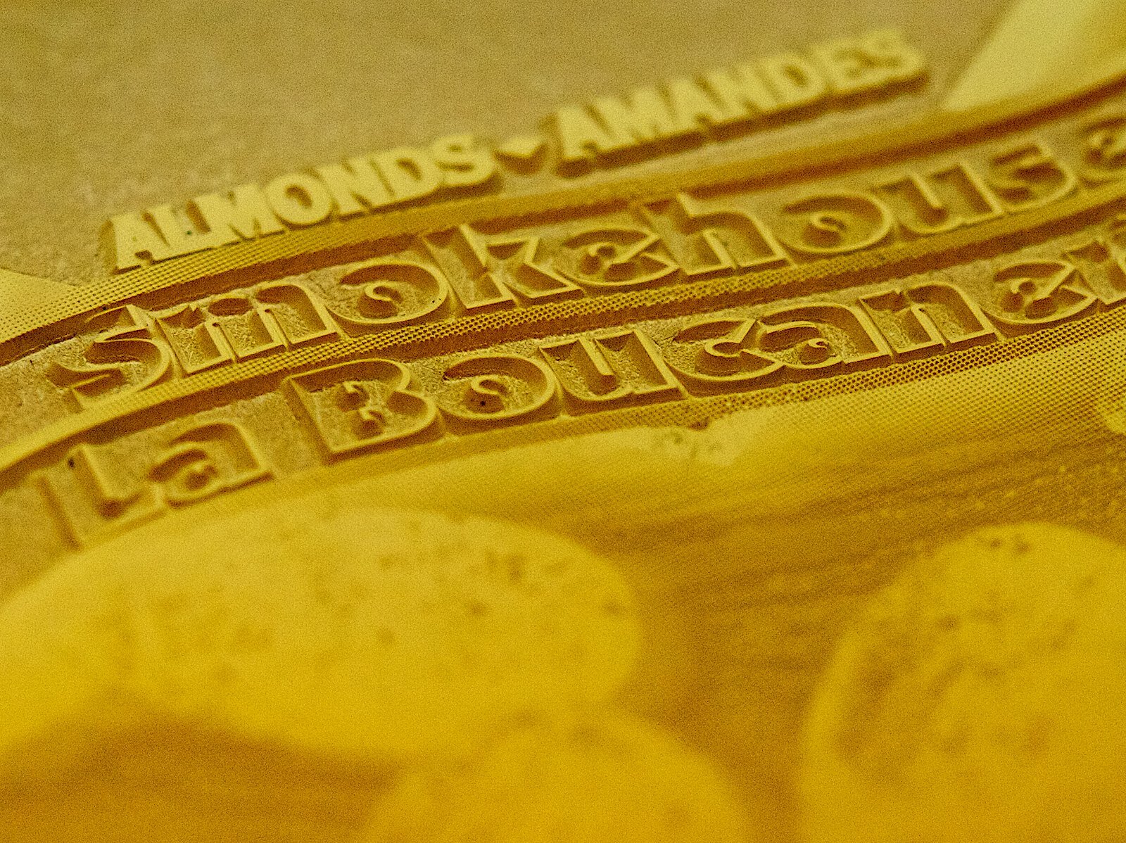 Zdjęcie przedstawia zbliżenie na formę drukową fleksograficzną, wykonaną z płyty fotopolimerowej. W centralnej części zdjęcia widoczne różne napisy na formie drukowej.