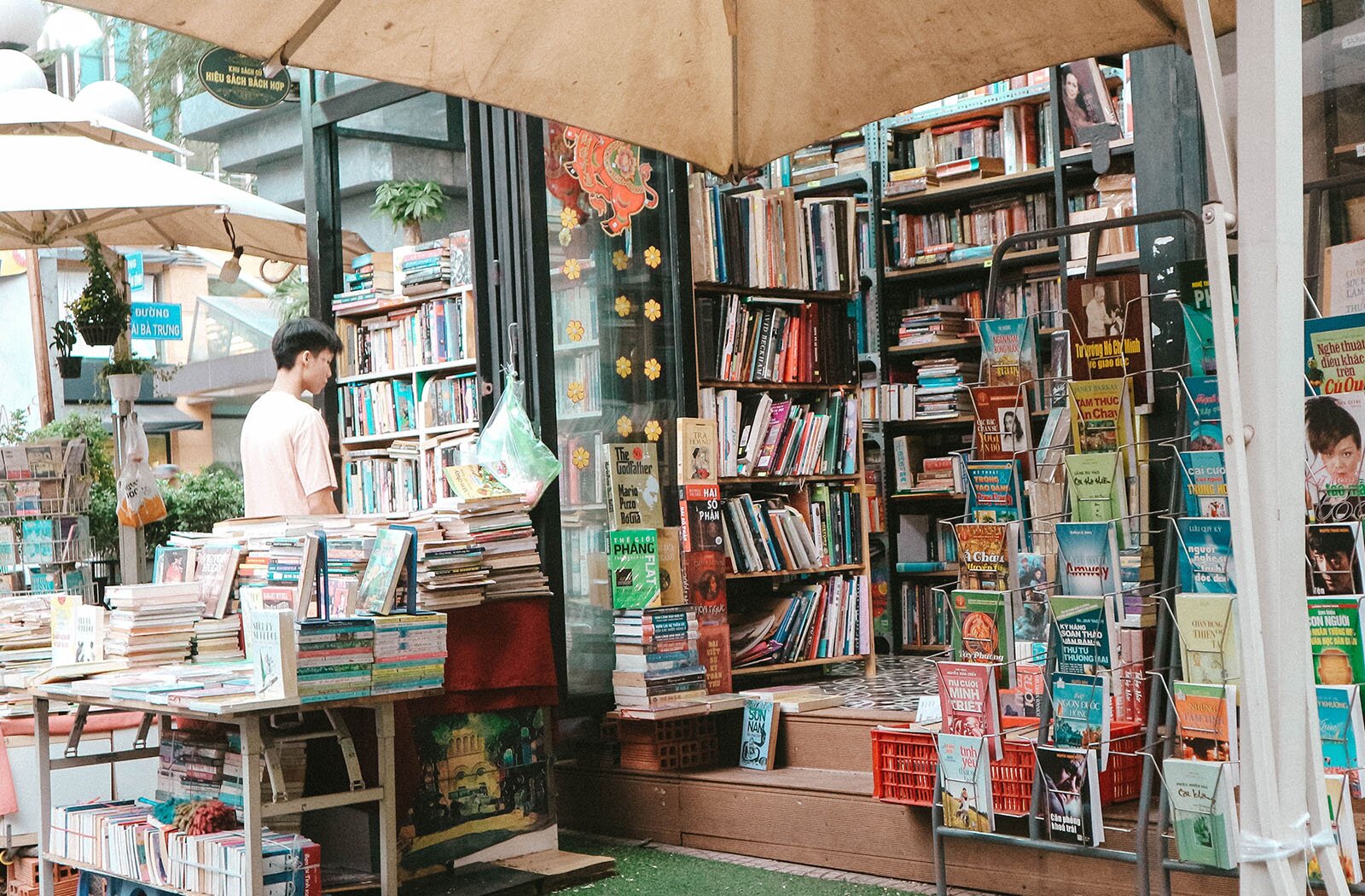 Zdjęcie przedstawia wnętrze księgarni. Przy jednej z półek stoi młody mężczyzna i przygląda się książkom.