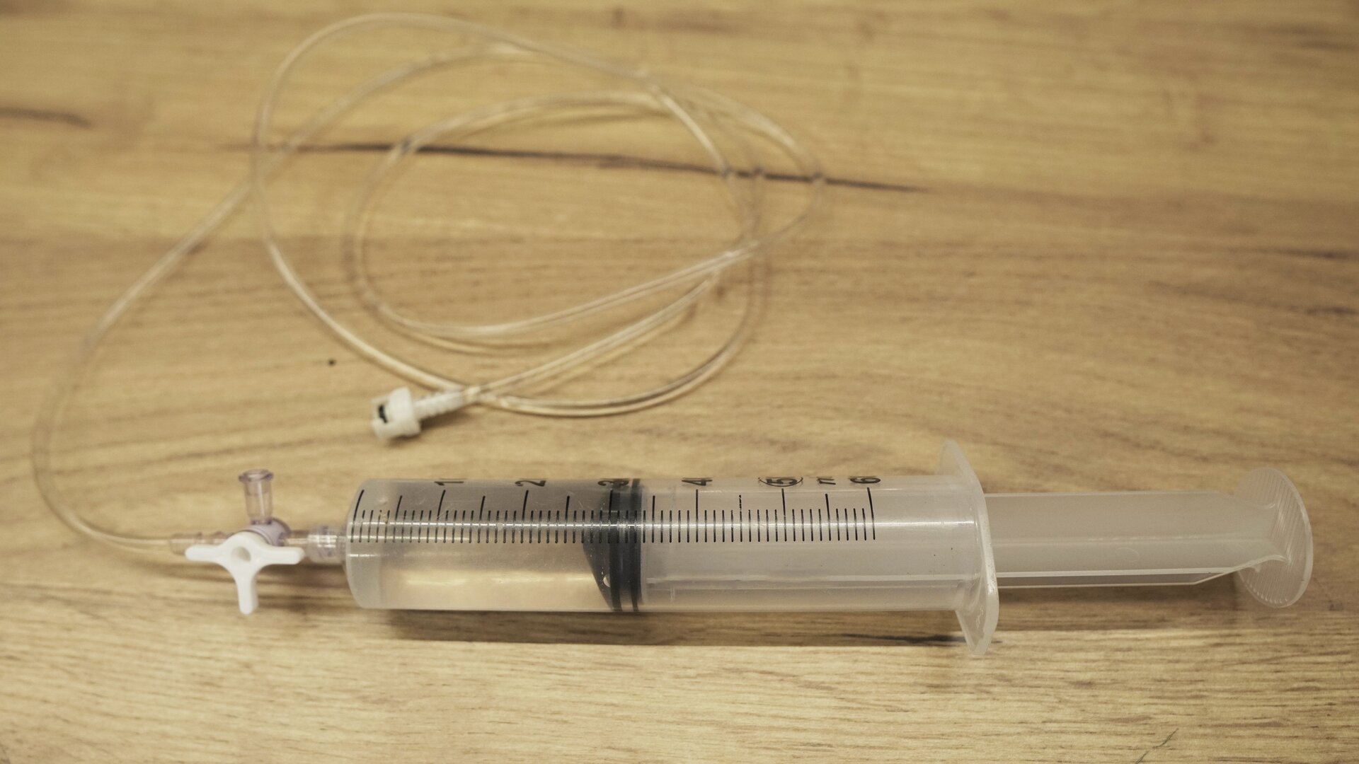 Na zdjęciu przedstawiona jest plastikowa strzykawka do połowy wypełniona wodą. 