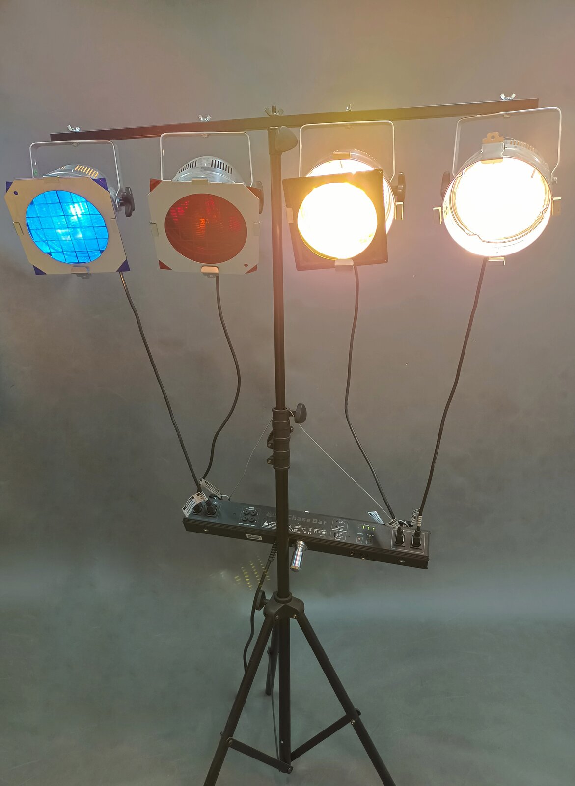 Zdjęcie przedstawia zestaw lamp z filtrami mocowany na statywie, w którego skład wchodzą dwie lampy świecące światłem naturalnym, jedna lampa świecąca światłem czerwonym dzięki nałożonemu filtrowi i jedna lampa świecąca światłem niebieskim dzięki nałożonemu filtrowi. 