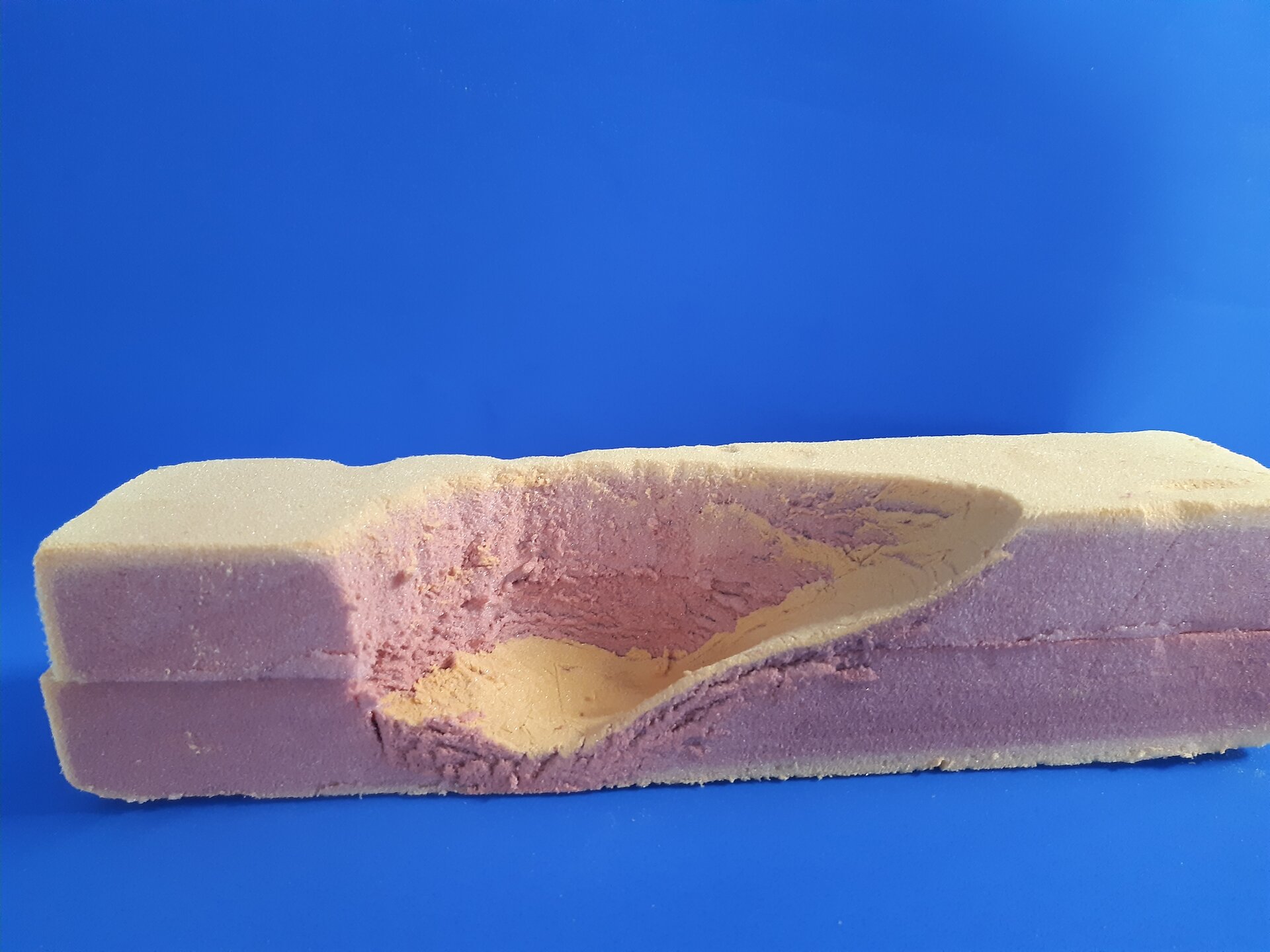 Zdjęcie przedstawia przekrój kształtu wycisku stopy w bloku pianki widzianej z boku.