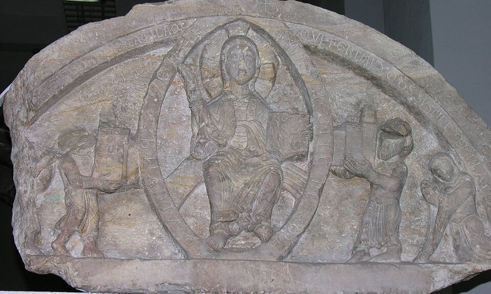 Fotografia przedstawia tympanon fundacyjny opactwa w Ołbinie, na którym znajdują się płaskorzeźby. W centralnej części jest płaskorzeźba Chrystusa w mandroli - jest to owalny okrąg otaczający jego postać. Chrystus jest przedstawiony jako mężczyzna w pozycji siedzącej odziany w długie szaty. Ma dłuższe włosy, a dookoła jego głowy znajduje się aureola. W lewej ręce trzyma księgę. Po obu jego bokach klęczą dwie mniejsze postacie – Bolesław Czwarty Kędzierzawy i jego syn Leszek.