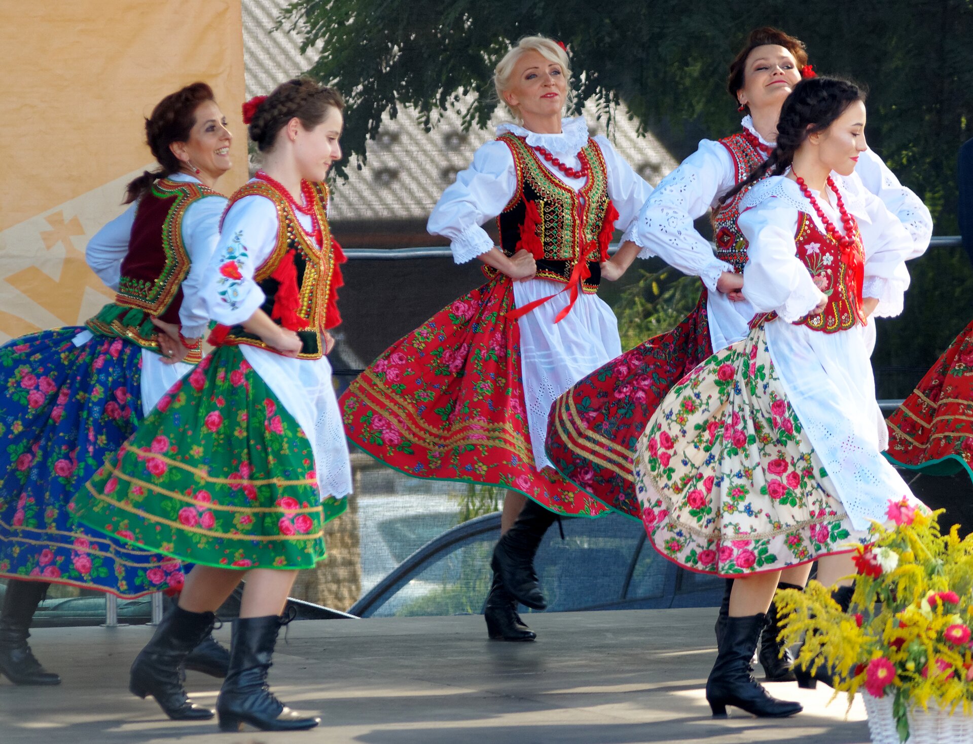 Zdjęcie przedstawia scenę, na której tańczy pięć młodych kobiet w polskich strojach ludowych.