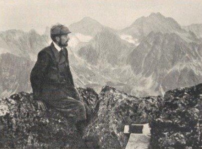 Ilustracja przedstawia mężczyznę w szarym ubraniu i kaszkiecie, na tle wysokich gór. Mężczyzna siedzi na jednym ze wzniesień pasma górskiego.