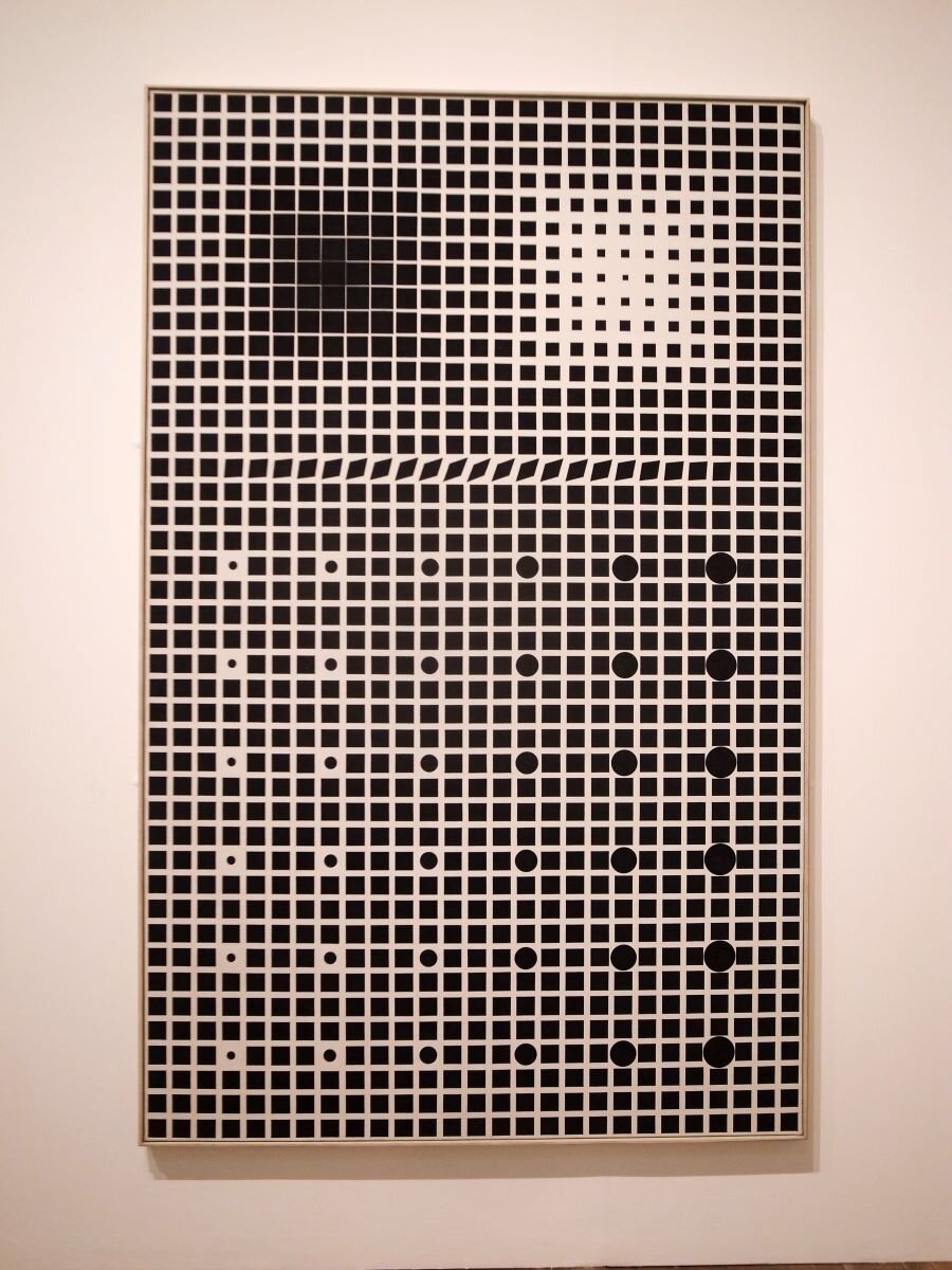 Ilustracja przedstawia dzieło Victora Vasarely'ego „Supernowa”. Obraz ukazuje czarne tło podzielone białymi liniami na setki malutkich, jednakowej wielkości kwadratów. Jest to kratownica. W miejscach niektórych kwadratów artysta umieścił koła białe i czarne, mniejsze i większe. W niektórych miejscach białe linie są cieńsze lub grubsze. Całość tworzy złudzenie optyczne. W pracy „Supernowa" Vasarely odwołuje się do znanego w optyce złudzenie Hermana. Artysta zestawiając ze sobą silnie kontrastujące elementy na planie kratownicy, uzyskał efekt iluzji pojawiania się ciemnych punktów w miejscach przecięcia białych linii. W swoim obrazie Vasarely jednocześnie poddaje analizie i dowartościowuje znaczenie iluzji optycznych w sztuce.