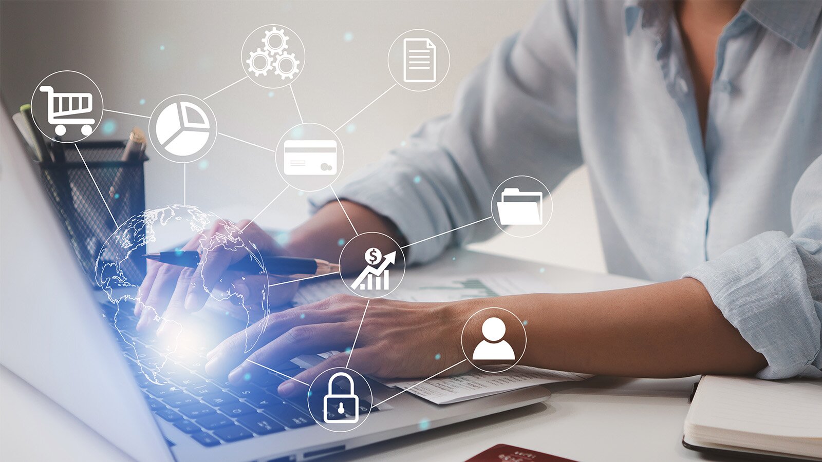 Grafika przedstawia osobę siedzącą przed ekranem komputera i piszącą coś na klawiaturze. Wokoło, wiszące w powietrzu widoczne są ikony: banku, kłódki, wózka sklepowego, karty kredytowej, giełdy. 