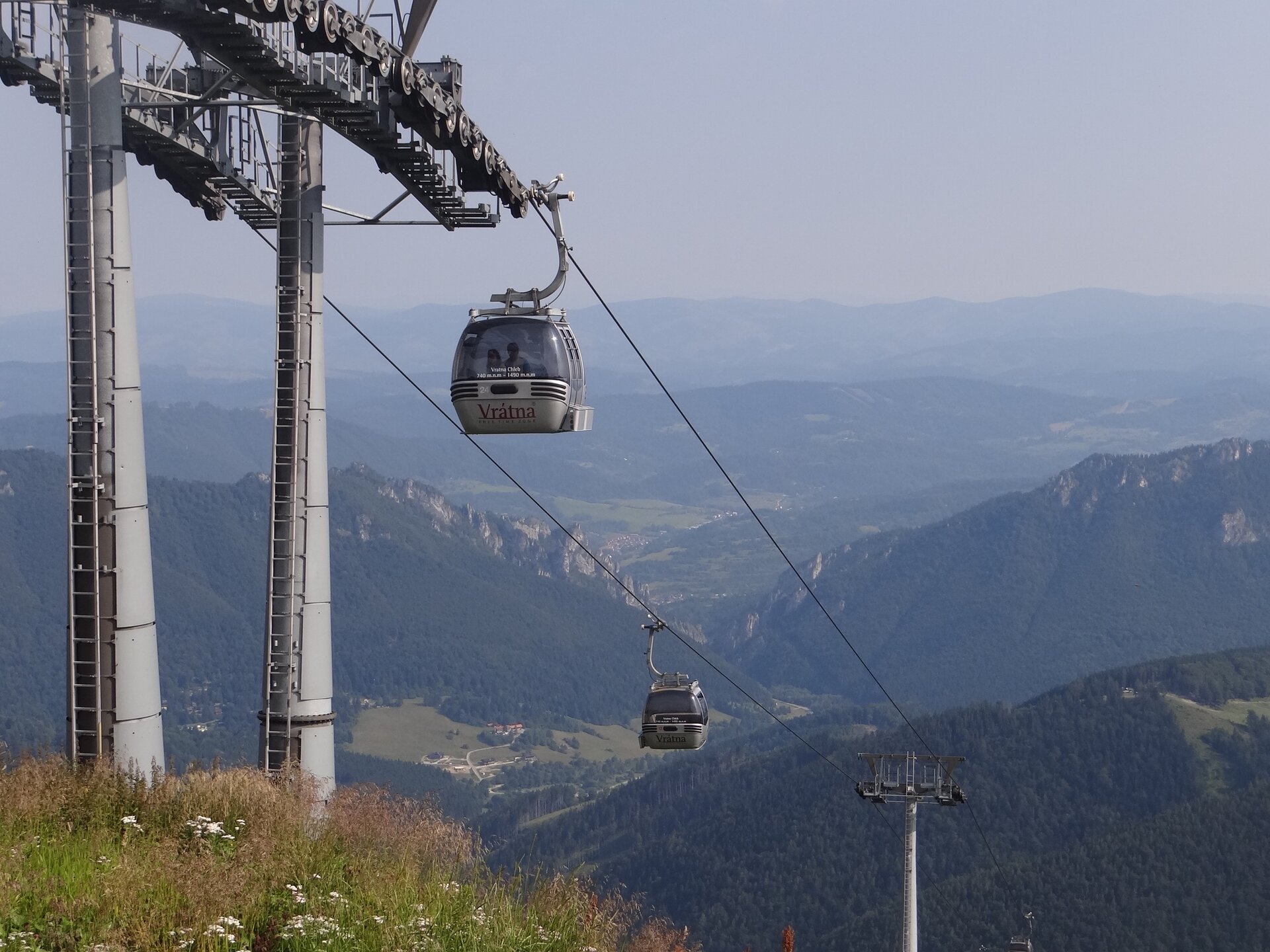 Na zdjęciu wyciąg kolejki kabinowej. W tle panorama pasma górskiego. 