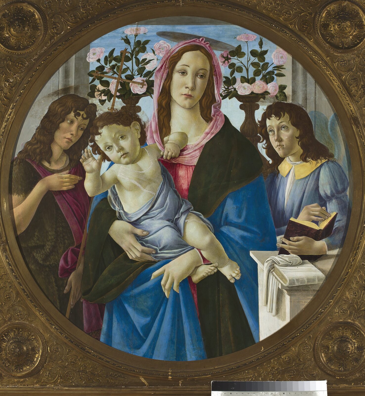 Ilustracja przedstawia obraz Sandro Botticelli „Madonna z Dzieciątkiem, Św. Janem i Aniołem”. Na obrazie widzimy Madonnę w czarno-różowej sukni, z nakryciem głowy. Kobieta na rękach trzyma dzieciątko, które w pasie ma założoną niebieską chustę. Wyciąga ono jedną dłoń w stronę odbiorcy obrazu. Po bokach Madonny stoją dwie inne postacie, o długich, ciemnych włosach. Jedna z nich trzyma książkę. Wszystkie postacie mają smutny wyraz twarzy. W tle znajdują się wazony z kwiatami. 