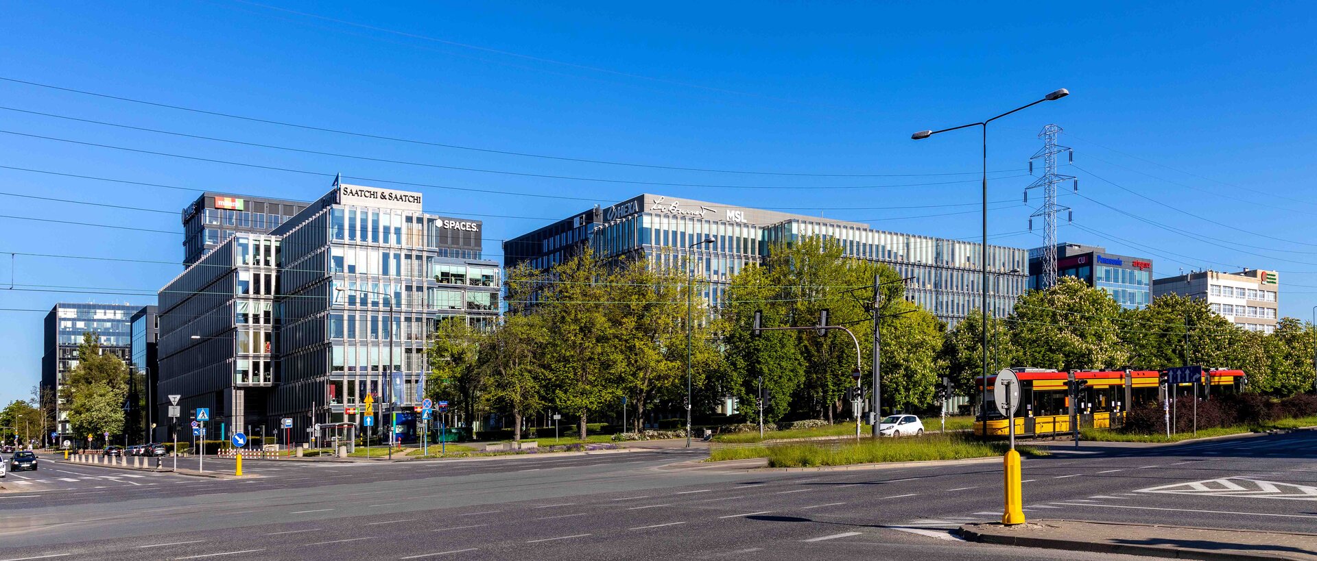 Zdjęcie przedstawia budynki biurowe o dużych oszklonych przestrzeniach.