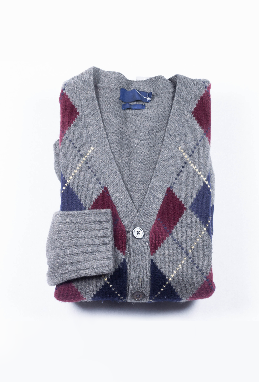 Seria zdjęć obrazująca wykorzystanie przewodników i izolatorów ciepła. Izolator cieplny – sweter, szaro‑czerwony‑granatowo‑biały kardigan w romby, zrobiony z wełny.