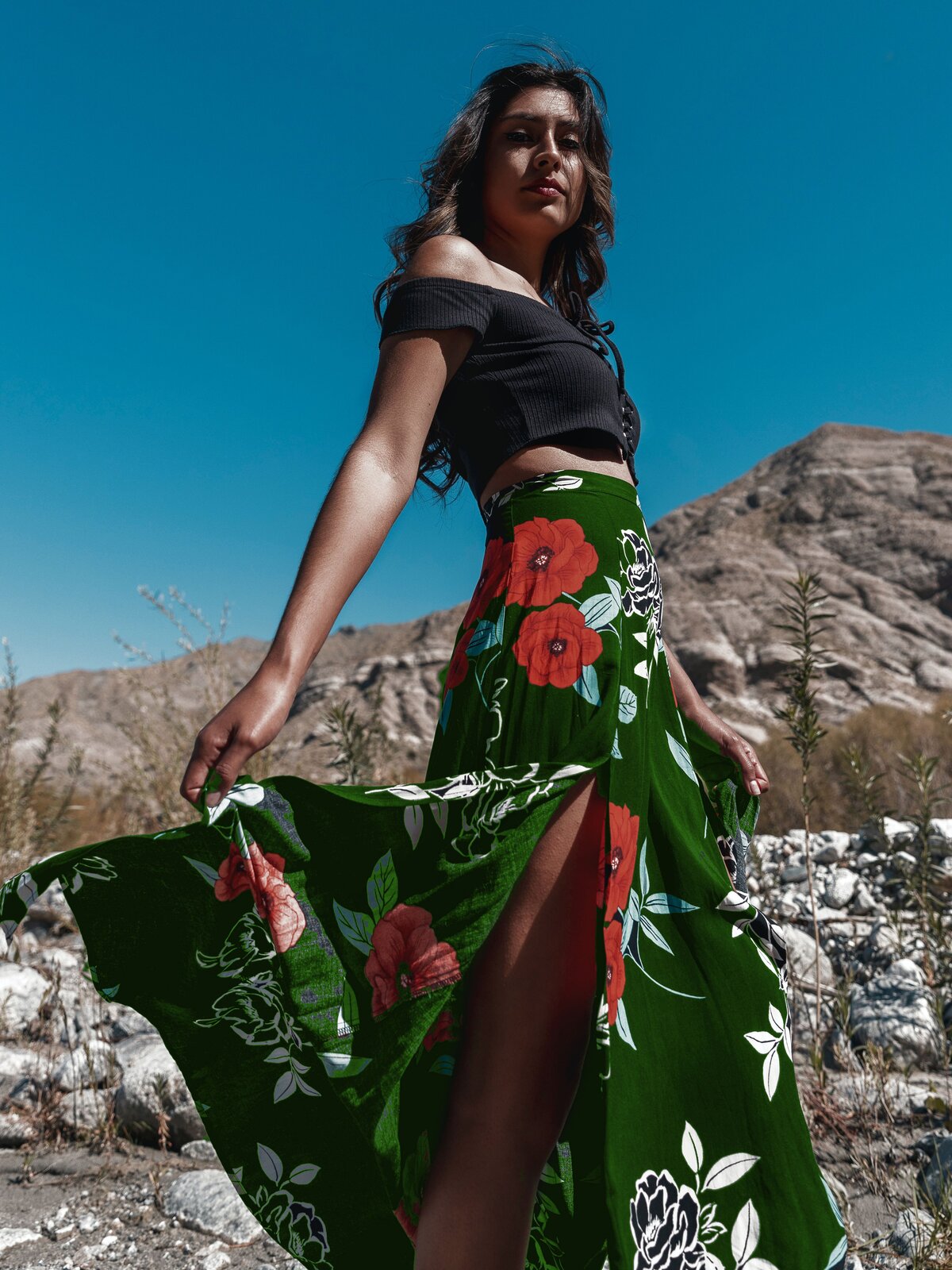 Zdjęcie przedstawia młodą kobietę, która ubrana jest we wzorzystą, rozkloszowaną spódnicę oraz czarny top. 