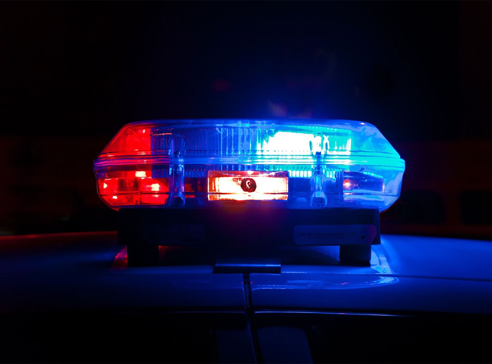 Zdjęcie przedstawia zbliżenie na błyskające światła na radiowozie. Światło jest w kolorze niebieskim i czerwonym. 