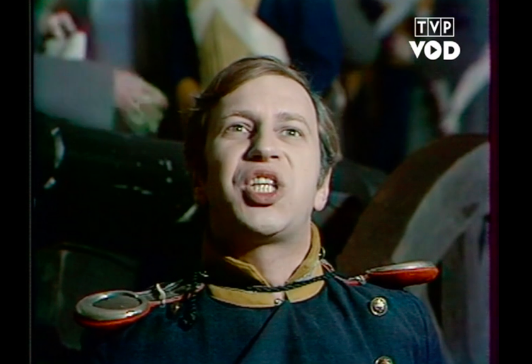 Fotografia przedstawia mężczyznę w sile wieku. Postać ukazuje w całości owalną twarz. Unosi głowę. Mężczyzna ma jasne, krótkie włosy zaczesane na prawą stronę. Jego czoło jest gładkie i wysokie. Ma jasne brwi i niewielkie oczy. Patrzy w górę. Mężczyzna ma prosty nos i otwarte, wydatne usta. Postać odsłania zęby. Mężczyzna jest ubrany w mundur.