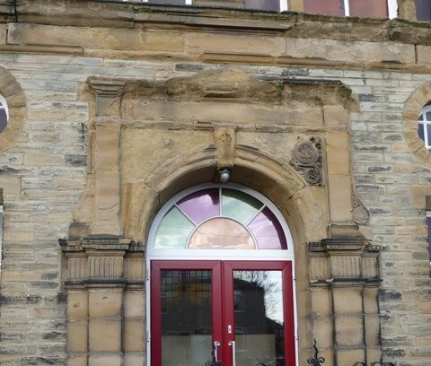 Zdjęcie przedstawia zniszczone ozdobne wejście do kaplicy. Zniszczona ściana ma jasnobrązowy kolor.  