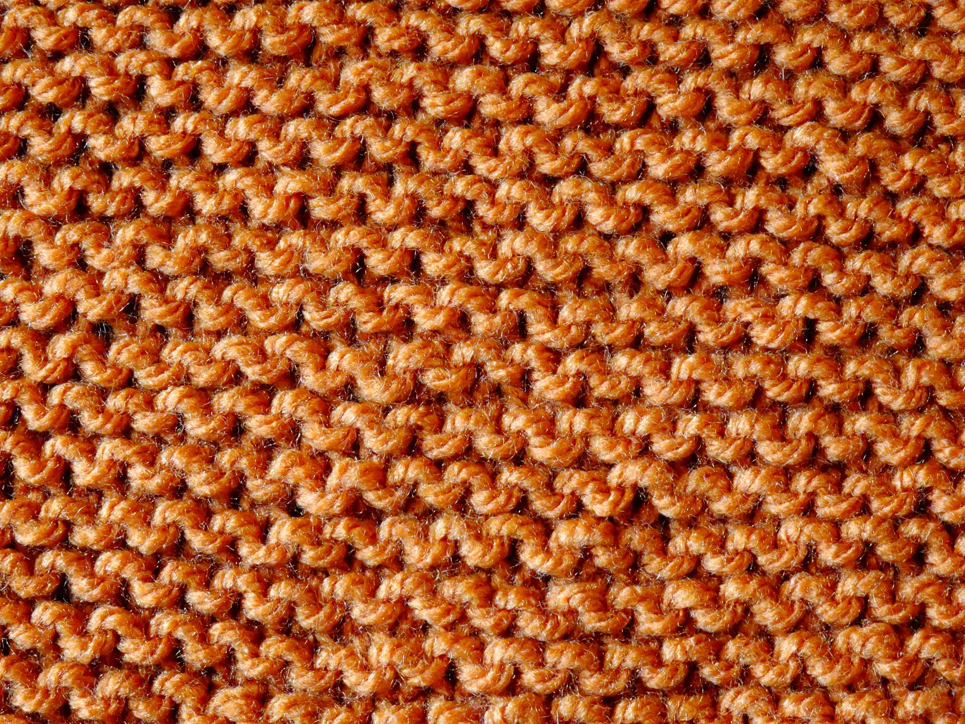 Zdjęcie przedstawia lewą stronę fragmentu pomarańczowej dzianiny rządkowej o splocie lewoprawym.Nagranie tożsame z treścią.