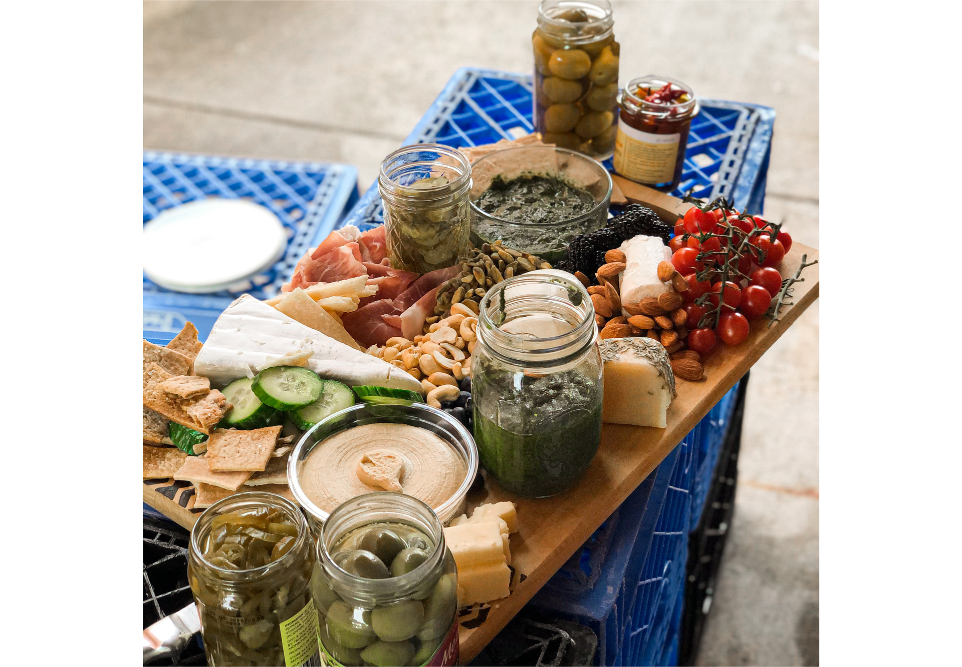 Zdjęcie przedstawia deskę kuchenną, na której serwowane są specjały kuchni włoskiej: oliwki, wędliny, różne gatunki sera, pomidory koktajlowe, ostre papryczki, migdały, orzechy.