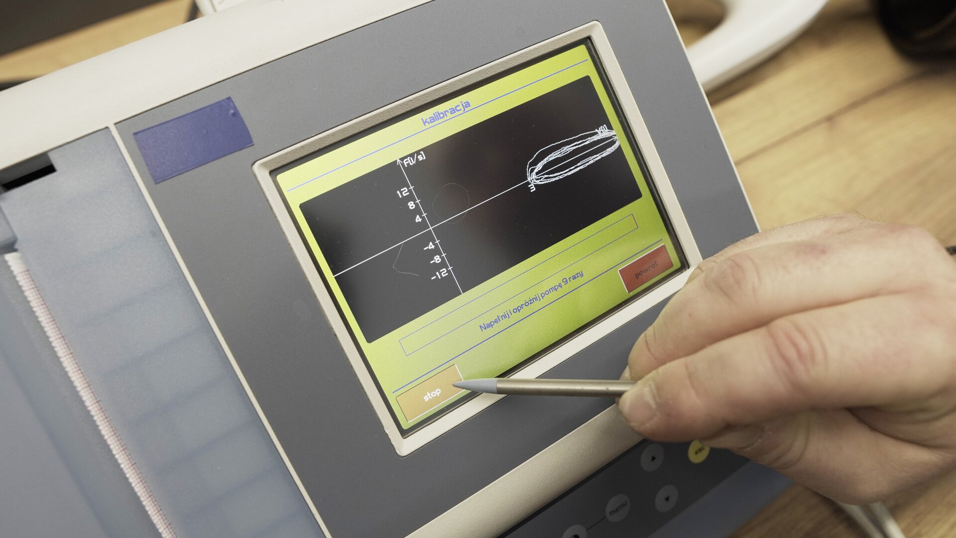 Na zdjęciu pokazano przybliżenie ekranu spirometru. Technik wybiera na klawiaturze ekranowej przycisk stop.