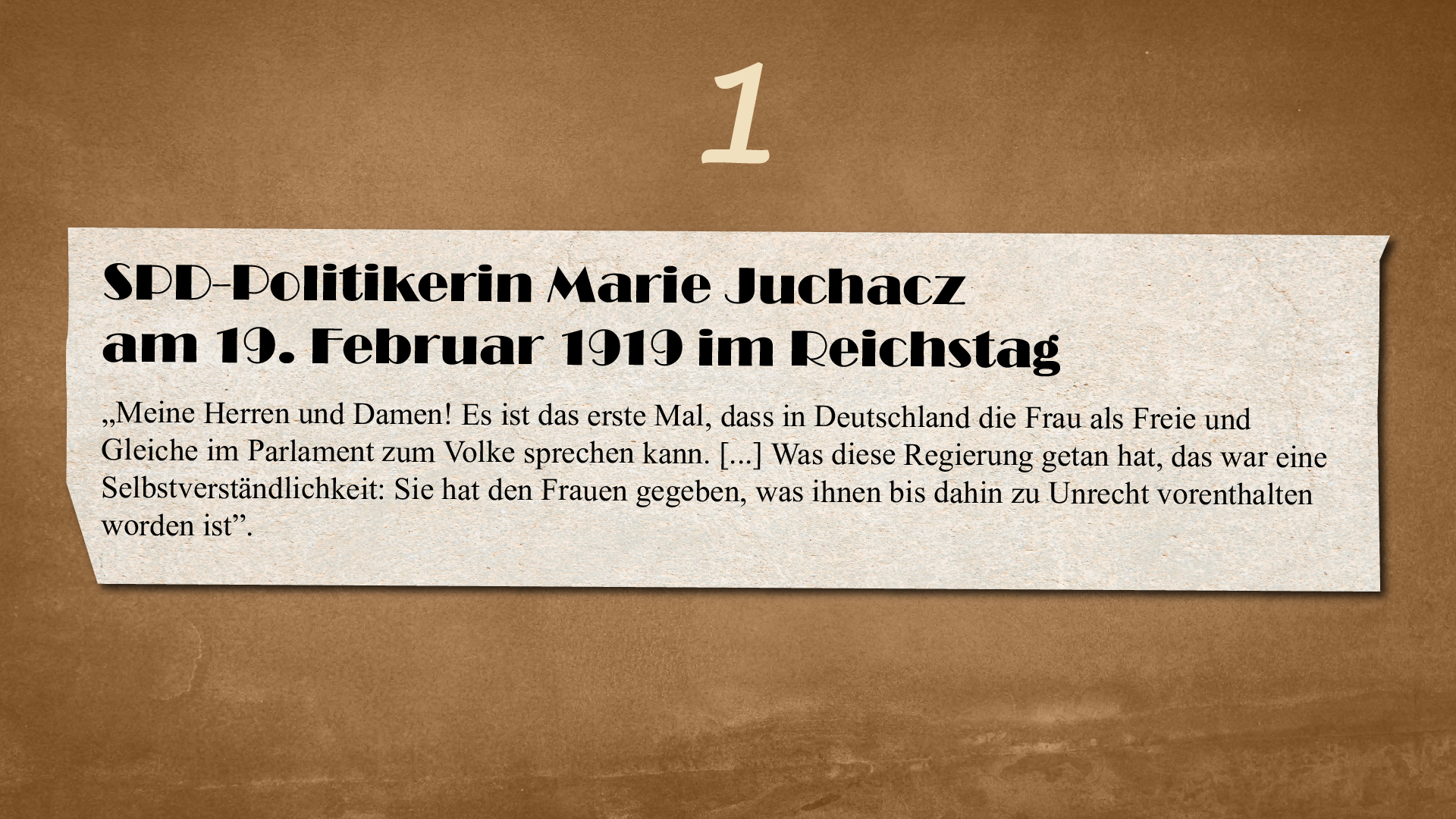 Ilustracja przedstawia kartkę o nierównych brzegach na ciemnym tle. Nad kartką znajduje się cyfra 1. Na kartce widnieje następujący tekst: 
SPD‑Politikerin Marie Juchacz am 19. Februar 1919 im Reichstag 
„Meine Herren und Damen! Es ist das erste Mal, dass in Deutschland die Frau als Freie und Gleiche im Parlament zum Volke sprechen kann. [...]Was diese Regierung getan hat, das war eine Selbstverständlichkeit: Sie hat den Frauen gegeben, was ihnen bis dahin zu Unrecht vorenthalten worden ist“.
